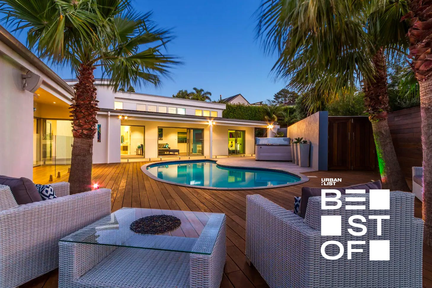 A lovely expansive deck looks out across a pool at dusk in one of the best pet friendly accommodation in NZ.